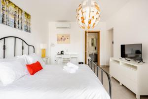 a white bedroom with a large white bed with a red pillow at Casa Leon Malta in St Julian's