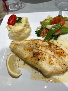 a plate of food with a piece of fish and vegetables at Cap d’Agde Centre port avec parking privé et belle vue port et mer in Cap d'Agde