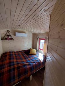 Margaux B&B Babbita في Stokrooie: سرير في غرفة صغيرة ذات سقف خشبي