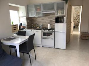 a kitchen with white appliances and a table with chairs at Le cheval d’en fer in Bégard