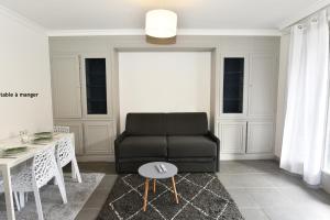 sala de estar con sofá negro y mesa en CONFORTABLE T2 AVEC PARKING PRIVE AU CENTRE de BRIVE en Brive-la-Gaillarde