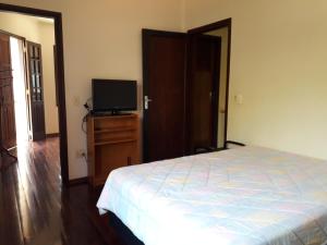 um quarto com uma cama e uma televisão de ecrã plano em Serra Negra Apartment em Serra Negra
