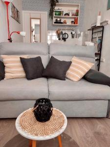 un sofá gris con almohadas y una mesa en la sala de estar en Le Cocon de Neptune en Arromanches-les-Bains