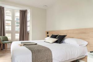 um quarto com uma cama grande com lençóis brancos e almofadas em Albatros em Puentedeume