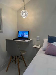 un ordenador portátil sentado en un escritorio junto a una cama en Studio Apartamento Lindo na Rua das Pedras, en Búzios