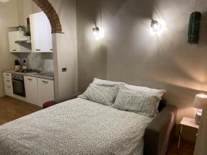 a bedroom with a bed with pillows and a kitchen at Casa Gallina in Volterra