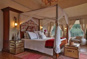 a bedroom with a canopy bed and a chair at Chamba Camp Thiksey in She