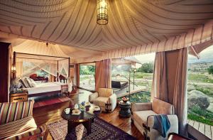 a bedroom with a bed and a large window at Chamba Camp Thiksey in She