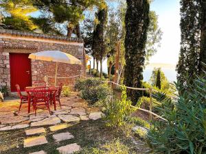 un patio con mesa, sillas y sombrilla en VIP View & Exclusive Access to the Sea, en Porto Santo Stefano