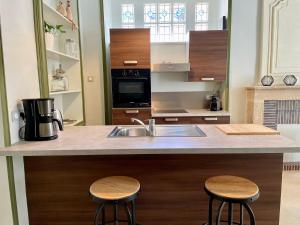 a kitchen with a sink and two bar stools at Le Petit Malo in Bayeux
