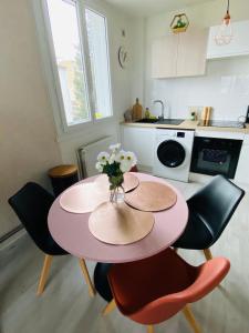 einen rosa Tisch mit Stühlen und eine Blumenvase in der Unterkunft Superbe appartement centre Montluçon, proche hôpital in Montluçon