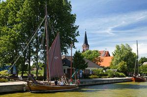 a sail boat in the water next to a church at Davids Ferienwohnung in Wustrow