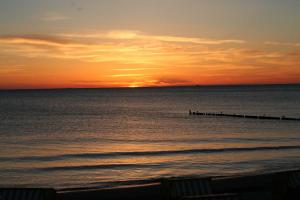 een zonsondergang boven de oceaan met een pier bij Davids Ferienwohnung in Wustrow