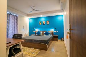 a bedroom with a blue wall with a bed and a desk at FlxHo Uno - Serviced Apartment & Rooms - Golf Course Road in Gurgaon +35 photos