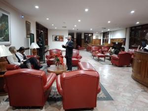 a man standing in a waiting room with red chairs at Hotel Negreiros in São Lourenço