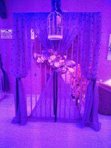 um quarto com cortinas e flores roxas e uma gaiola para pássaros em Batw باتوا لشقق المخدومة em Al Baha