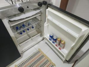 a small refrigerator with its door open in a kitchen at Pasargada Praia da Costa in Vila Velha