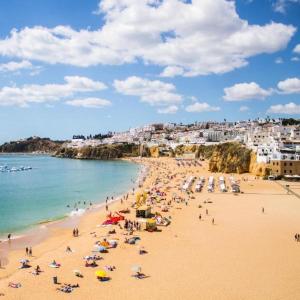 eine Gruppe von Menschen am Strand mit dem Meer in der Unterkunft Ana Sun in Albufeira