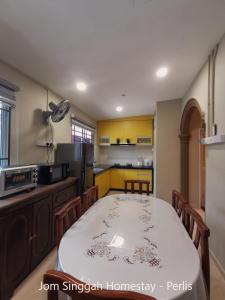a kitchen with a table and a kitchen with yellow cabinets at Jom Singgah Homestay - Perlis in Kangar