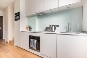 uma cozinha com armários brancos e um lavatório em Covent Garden Luxury Retreat em Londres