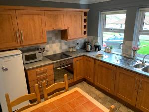 a kitchen with wooden cabinets and a table and chairs at Brada View Bamburgh in Bamburgh +37 photos