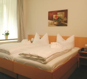 a bed with white pillows on it in a room at GesundheitsHotel Das Bad Peterstal in Bad Peterstal-Griesbach