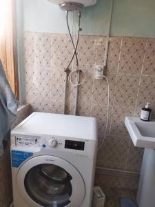 une petite salle de bains avec un lave-linge et un lavabo dans l'établissement Buuzara Guest House, à Batken