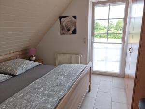 a bedroom with a bed and a large window at Windlicht im 1 Stockwerk in Norddeich