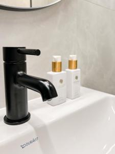 a bathroom sink with a black faucet and three candles at Apartamenty LUNA in Świeradów-Zdrój