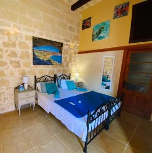 1 dormitorio con 1 cama con almohadas azules en Gozo Sunset Guesthouse, en Qala