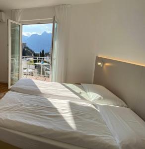 a white bed in a room with a window at Albergo Garni Francesco in Nago-Torbole +88 photos