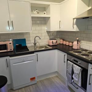 una cucina con armadi bianchi e lavandino di Ground floor well appointed cosy flat in Ludlow a Ludlow