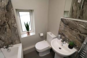 La salle de bains est pourvue de toilettes blanches et d'un lavabo. dans l'établissement Cosy Two Bedroom Cottage, à Whitehaven