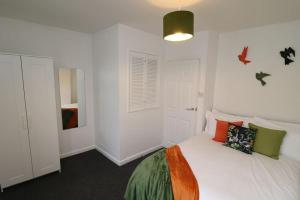 a white bedroom with a bed with colorful pillows at Cosy Two Bedroom Cottage in Whitehaven