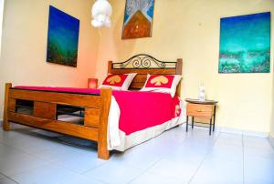 a bedroom with a large wooden bed with red sheets at NAFI'0 in Gorée