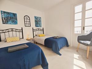 a bedroom with two beds and a chair at Villacana Playa Silvia in Estepona