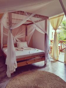 a bedroom with a canopy bed with a rug at Hakuna Matata Boutique in Paje
