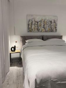 a bedroom with a white bed and a painting on the wall at Downtown Chic 2 in Iaşi