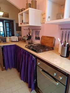 a kitchen with a stove and purple curtains on the counter at Cesare Battisti in Seggiano