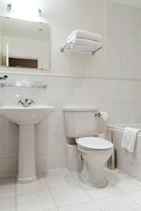 a white bathroom with a toilet and a sink at Hurtwood Hotel in Peaslake