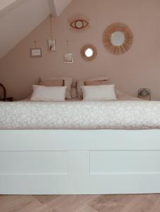 1 dormitorio con 1 cama blanca grande y 2 espejos en Perle rare, appartement paisible et cosy, en Lamballe