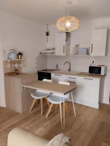cocina con mesa, sillas y fregadero en Perle rare, appartement paisible et cosy, en Lamballe
