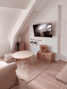 a living room with a table and a tv on the wall at Perle rare, appartement paisible et cosy in Lamballe +25 photos