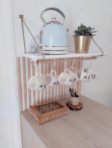 a shelf with coffee mugs and a pot on it at Perle rare, appartement paisible et cosy in Lamballe