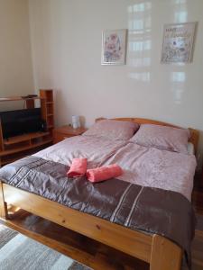 Una cama con dos almohadas rosas encima. en Börzsöny Aranya Vendégház, en Nagybörzsöny