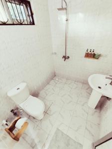 a white bathroom with a toilet and a sink at Hakuna Matata Boutique in Paje +42 photos