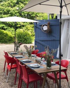 une table en bois avec des chaises rouges et un parasol dans l'établissement La Quietat Montbarla, à Montbarla