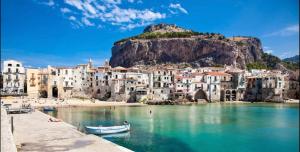 um grupo de edifícios numa praia com uma montanha em Antica Cefalu' em Cefalù