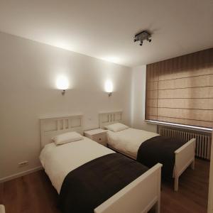 two beds in a small room with a window at Stijlvol appartement met zeezicht Nieuwpoort in Nieuwpoort
