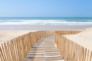 een houten hek op een strand met de oceaan bij locationestivale40 Bungalow petit budget océan forêt in Bias